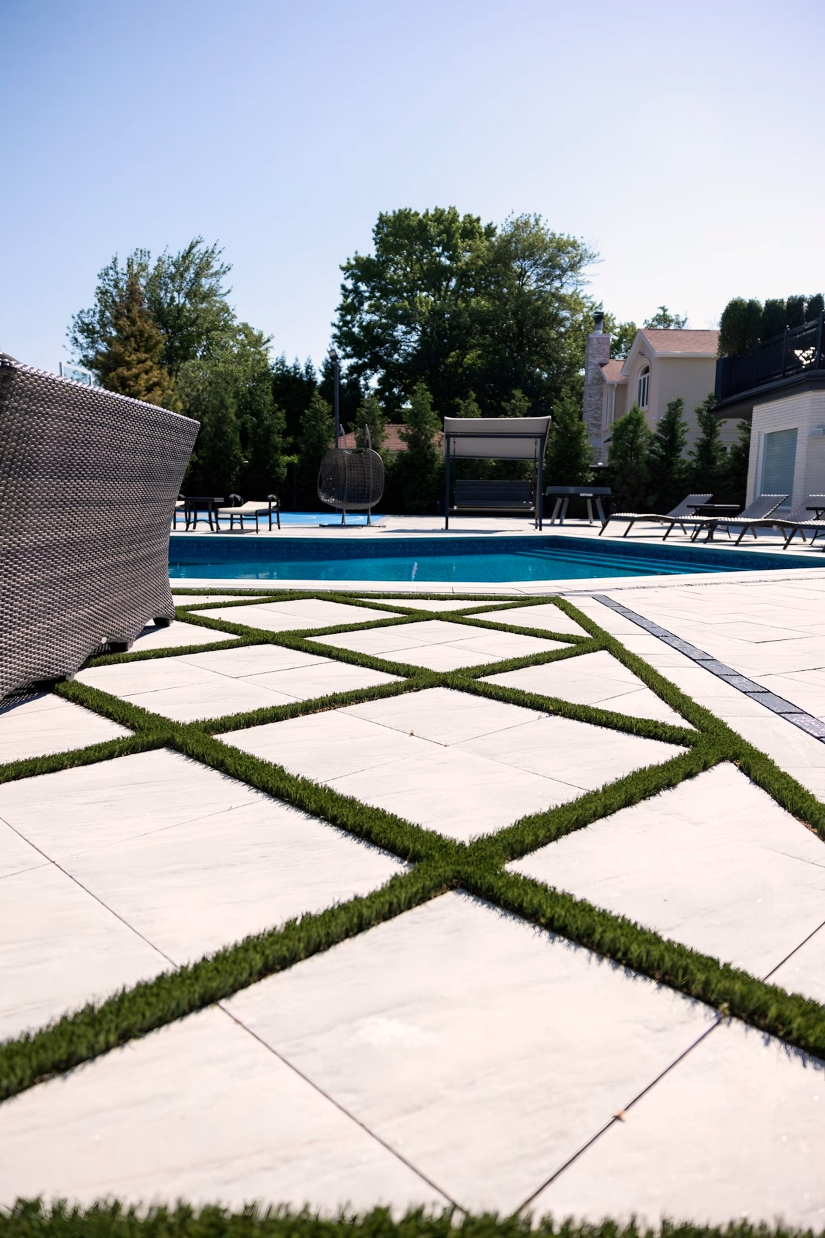 Large pavers with artificial turf joints beside a backyard pool